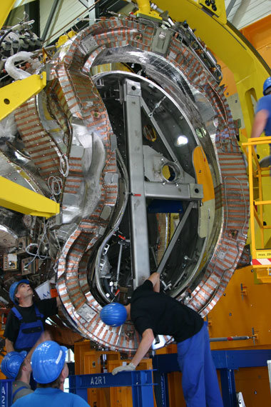 Aus den Rechnungen der Plasmaphysiker und Konstrukteure sind fertige Spulen
geworden, hier beim Auffädeln auf das Plasmagefäß.